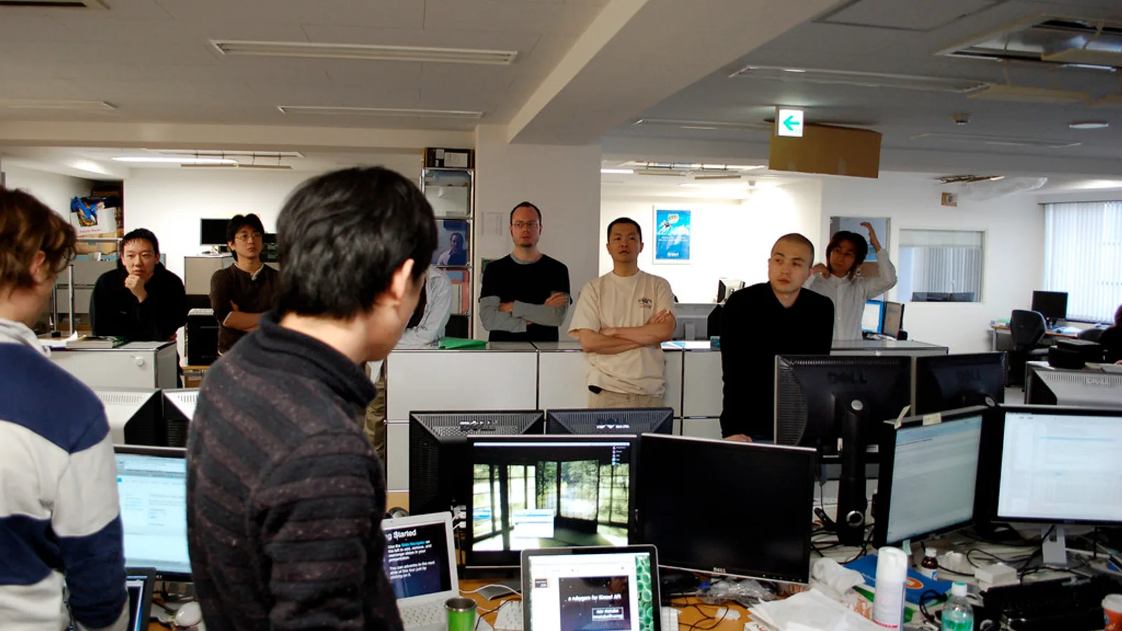 Small team standing around a whiteboard during a short office review meeting
